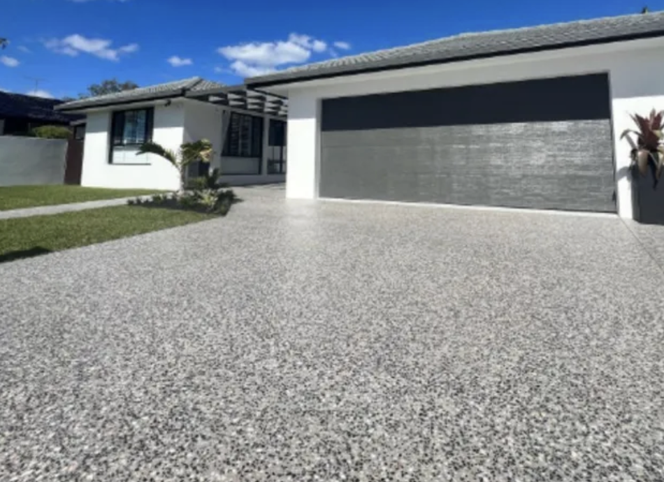 Exposed aggregate concrete driveway with speckled pebble finish at a modern home in Atlantic Beach, FL